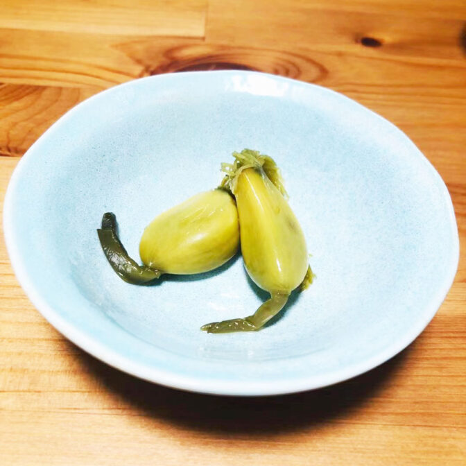 にんにくの根っこから葉茎までそのまままるごとピクルス！ 深谷の新鮮な発芽にんにくを斬新な製法でまるごと漬け込みました。 ピクルスが苦手と言う方でもお酢がとてもマイルドな仕上がりになっており、数種類のハーブが効いた大人のピクルスに仕上がっています。