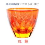 グラスにお酒を入れるとグラス底面に彫刻した模様が側面に映り込み赤く染まる紅葉が広がる、砂切子ならではの不思議なグラスです。 オレンジの素地に鮮やかな金赤を被せた2重構造の被せ硝子を使用し、側面では赤く染まった紅葉が最後の輝きを見せ、お酒を注ぐと底面の紅葉が側面に映り込み紅葉が舞い落ちる様子を表現しています。