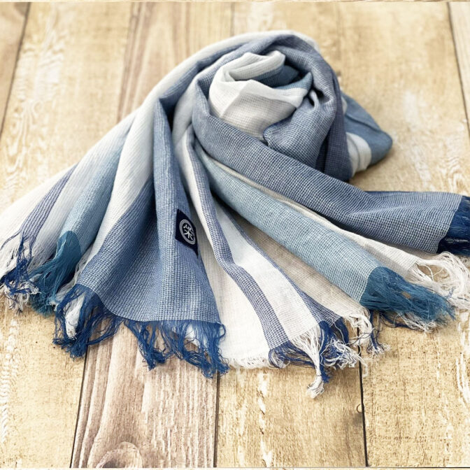 江戸の中期より織られておりました和田縞紬を再現した、セルヴィッチ生地（旧式織機を使って織られた生地）の薄手で柔らかな藍染のストール。手染めされた藍染の繊維をモダンなストライプに織り上げています。 春、夏、秋とフル活用でき、和洋どんなファッションにも合わせられるストールです。